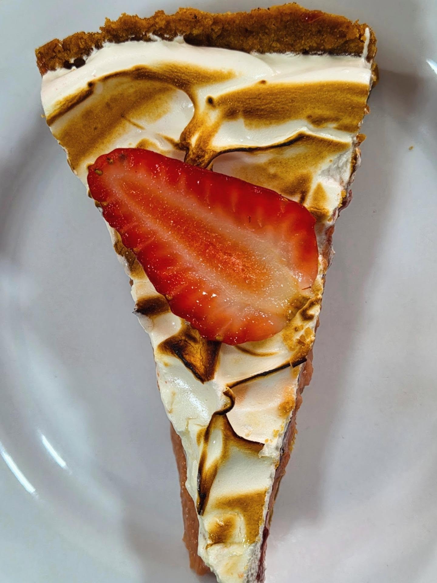 Fatia de torta de merengue tostado com morango fresco
